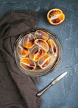 Bloody red sicilian oranges cut into quarters in vintage metal plate over concrete textured background