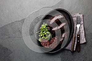 Bloody sausages - chilean preta on iron plate, top view, grey slate background photo