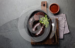 Bloody sausages - chilean preta on iron plate, top view, grey slate background