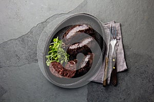 Bloody sausages - chilean preta on iron plate, top view, grey slate background photo