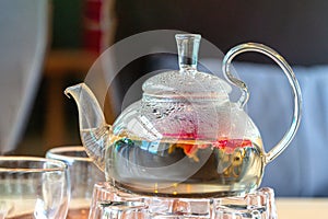 Blooming green tea in glass teapot on a wooden table in a bar or coffee shop