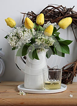 blooming lilacs and yellow tulips in a white jug on the table. floristry, making bouquets. spring composition with photo