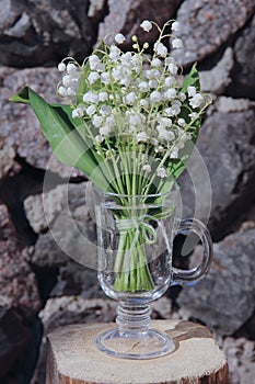 Blooming lilies in an elegant glass on the stones background.