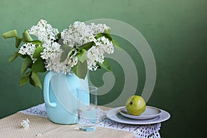 Blooming white lilac in a jug. Still life in rustic style.