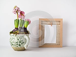 Blossom hyacinth in flower pot and blank piece of white card in wooden frame