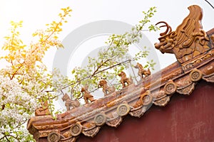 Blossoming pear flowers and eaves decorated with statue of beasts or animals