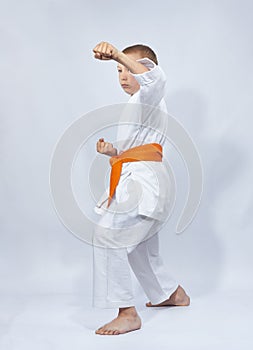 Blow arm karateka boy beats with an orange belt