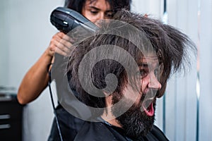 blow dry hair in barbershop of brutal mature shouting client man, hairdresser