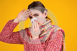 Blow the snot. Woman in sweater and scarf hold napkin blow snot isolated on yellow. Mucus flowing from nose. Girl with