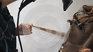 Blowing hair when staining. Drying long brown hair with a hair dryer and a round brush. Close-up.