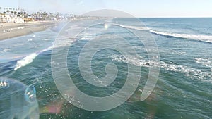 Blowing soap bubbles on ocean pier in California, blurred summertime background. Creative romantic metaphor, concept of