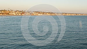 Blowing soap bubbles on ocean pier in California, blurred summertime background. Creative romantic metaphor, concept of