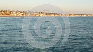 Blowing soap bubbles on ocean pier in California, blurred summertime background. Creative romantic metaphor, concept of