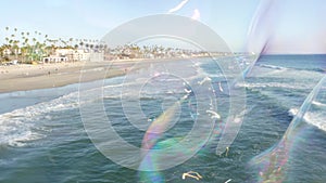 Blowing soap bubbles on ocean pier in California, blurred summertime background. Creative romantic metaphor, concept of dreaming