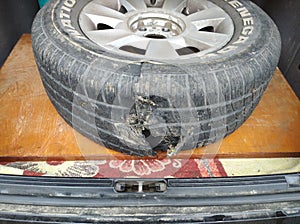 The blown-up damaged tire of the car`s wheel lies in the trunk photo