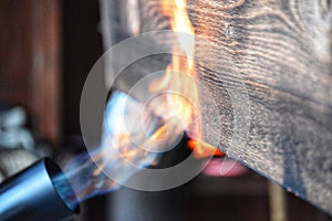 Blowtorch flames on a piece of wood showing shou sugi ban technique.