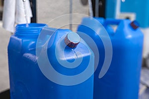 A blue 20 liter HPDE water container being refilled with purified H2O. The top cap already sealed with shrink wrap