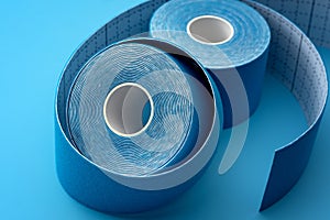 Blue Adhesive Physio or Kinesiology Tape Rolls on Matching Background Concept for Supportive Athletic Care, Enhancing Physical