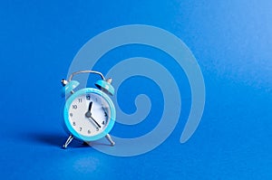 A blue alarm clock on a blue background. Limited offer and over time. Planning and discipline. waiting for a meeting. Punctuality