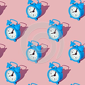 Blue alarm clock on a green background. Set. Seamless texture pattern. Long harsh shadow from the summer sunshine