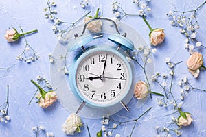 Blue alarm clock and pattern from fresh white gypsofila and rose flowers on blue textured background photo