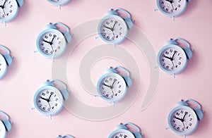 Blue alarm clocks on a pastel pink background