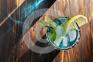 Blue alcoholic cocktail in a glass on a wooden bar counter