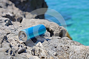 blue aluminum beverage can left behind on stone coast on mediterriean, problem of marine pollution