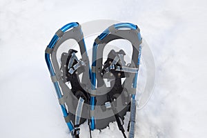 Blue aluminum snowshoes in a snowbank