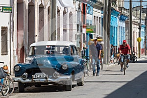 Blue american vintage car in the province Villa Clara with street life view