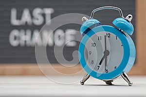 blue analog clock on the background of the text in English last chance