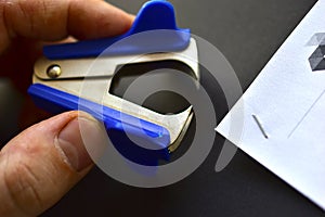 Blue anti-stepler paper clip or expander on a black background