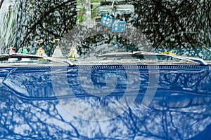 Blue antique car with reflections of trees