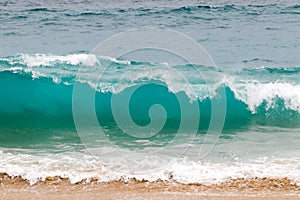 Blue and aquamarine color sea waves and yellow sand  with white foam. Marine beach background.