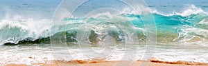 Blue and aquamarine color sea waves and yellow sand  with white foam. Marine beach background. Banner format.