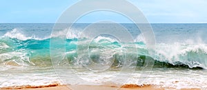 Blue and aquamarine color sea waves and yellow sand with white foam. Marine beach background. Banner format.