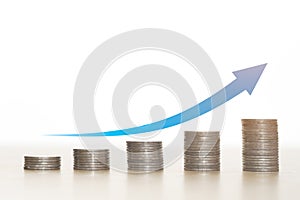 Blue arrow on top stack of coins white background.