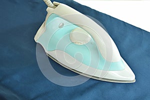 Blue automatic electric iron pressing cloth on ironing board