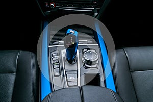 Blue Automatic gear stick transmission of a modern car, multimedia and navigation control buttons. Car interior details.
