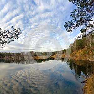 Blue autumn sky with clouds reflected in the pond