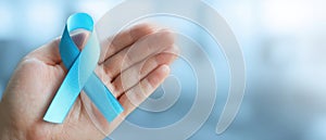 The blue awareness ribbon held in a person's hand symbolizing support and unity. AI generated image