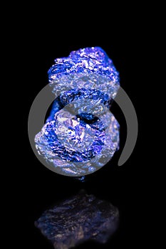 Blue Azurite mineral gemstone in front of black background, rough crystal