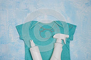 Blue baby bodysuit with stains and different types of stain removers. Dirty clothes. Stubborn stains. Clean linen. Flat lay,