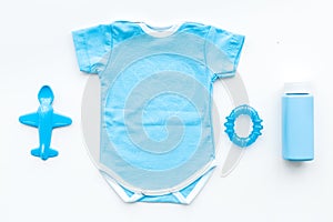 Blue baby clothes for little boy. Bodysuit, toys, cosmetics on white background top view