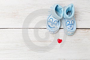 Blue baby`s bootees on wooden background. Mockup
