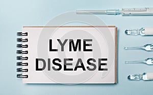 On a blue background ampoule with medicines and a notebook with the text LYME DISEASE. Medical concept