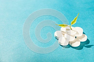 On blue background a bunch of white pills from the top growing plant. Concept medicine, medical, natural medicines