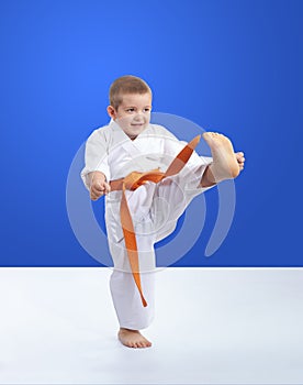 On a blue background karateka is training kick leg forward