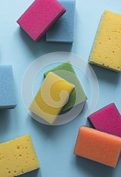 On a blue background lies a layout of different color sponges for cleaning the kitchen cleaning dishes
