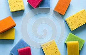 On a blue background lies a layout of different color sponges for cleaning the kitchen cleaning dishes